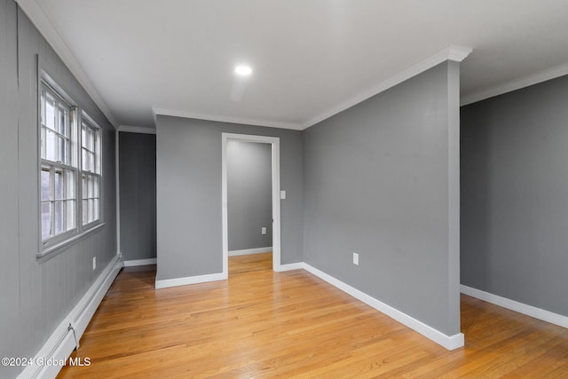 empty room with light wood-type flooring, crown molding, and baseboard heating