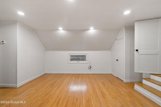 additional living space with light hardwood / wood-style flooring and lofted ceiling