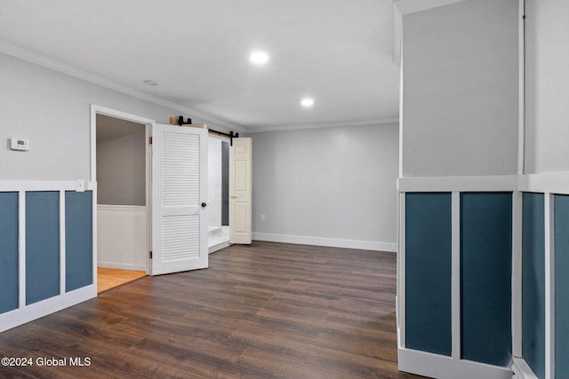 unfurnished room featuring a barn door, dark wood-type flooring, and ornamental molding