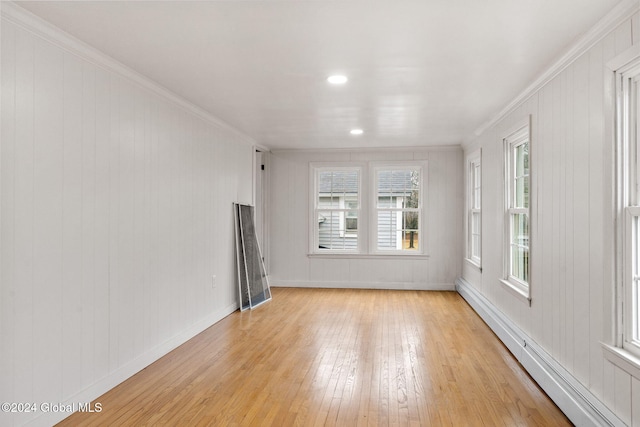 unfurnished living room featuring light hardwood / wood-style floors, crown molding, wooden walls, and a baseboard radiator