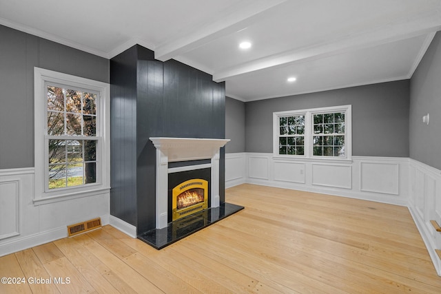 unfurnished living room with beamed ceiling, light hardwood / wood-style floors, and ornamental molding