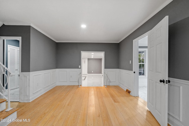 spare room with light wood-type flooring and crown molding