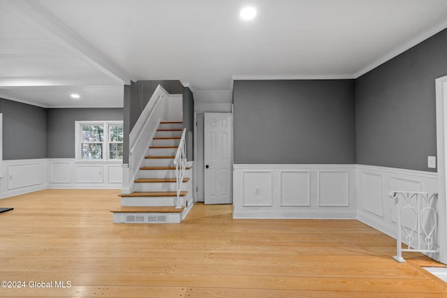 stairs featuring wood-type flooring and ornamental molding