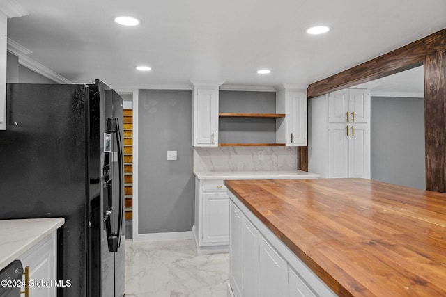 kitchen featuring butcher block counters, backsplash, black fridge, ornamental molding, and white cabinetry