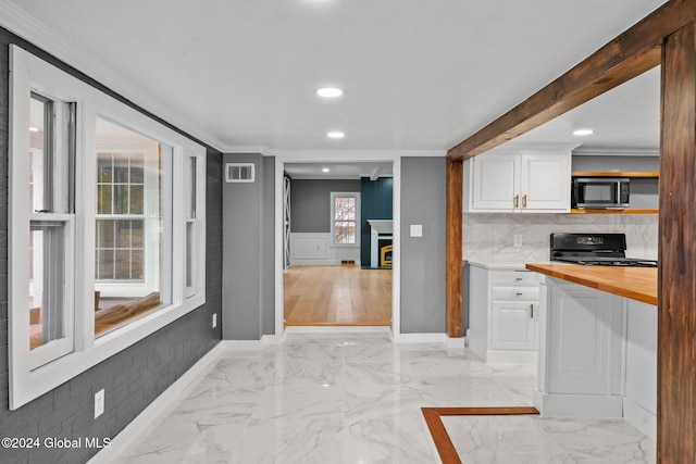 kitchen with wood counters, backsplash, black range, crown molding, and white cabinetry