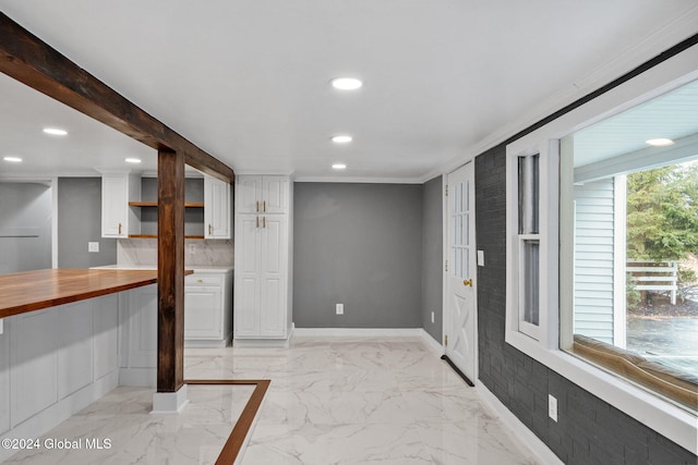 interior space with white cabinets, crown molding, wood counters, and a healthy amount of sunlight