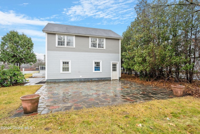 back of property with a lawn and a patio area