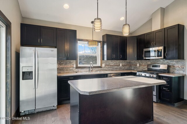 kitchen with a center island, hanging light fixtures, sink, light wood-type flooring, and appliances with stainless steel finishes