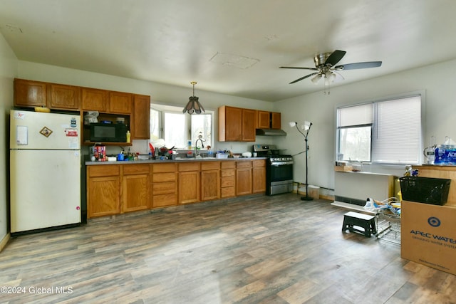 kitchen featuring pendant lighting, stainless steel gas stove, white refrigerator, and plenty of natural light