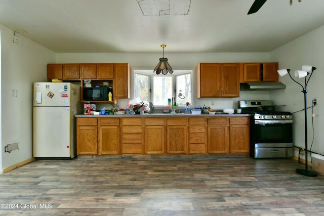 kitchen featuring decorative light fixtures, white fridge, dark wood-type flooring, and stainless steel range oven