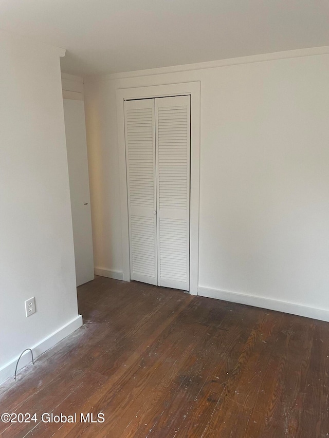 unfurnished bedroom featuring dark hardwood / wood-style floors and a closet