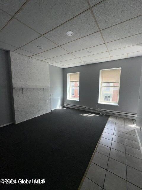 tiled spare room featuring a paneled ceiling and a baseboard radiator