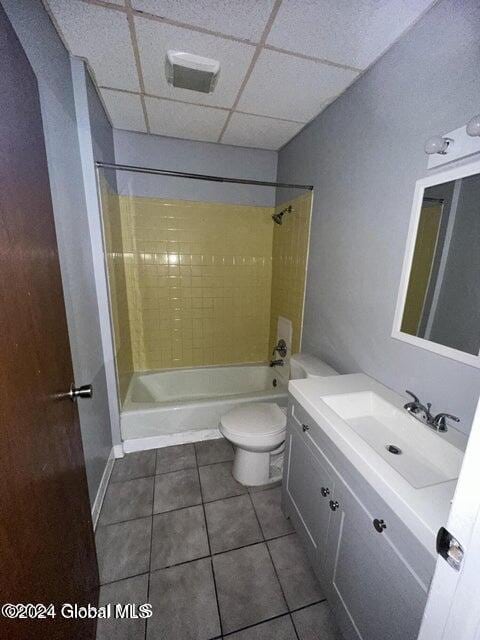 full bathroom featuring a paneled ceiling, shower / bath combination, vanity, tile patterned flooring, and toilet