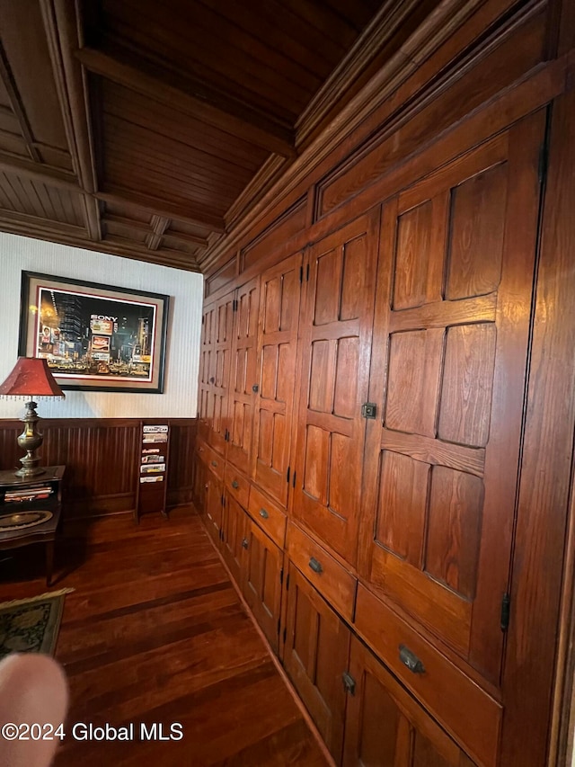 hall with beamed ceiling, dark hardwood / wood-style floors, and wood walls