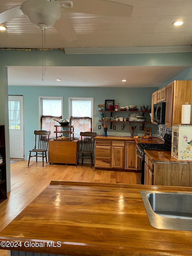 kitchen featuring gas stove, plenty of natural light, light hardwood / wood-style floors, and ornamental molding