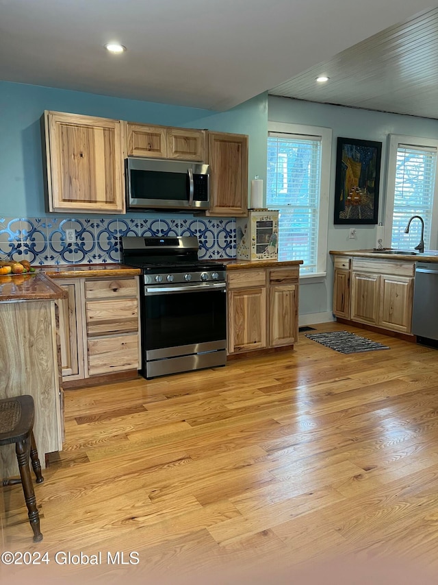 kitchen with plenty of natural light, sink, appliances with stainless steel finishes, and light hardwood / wood-style flooring