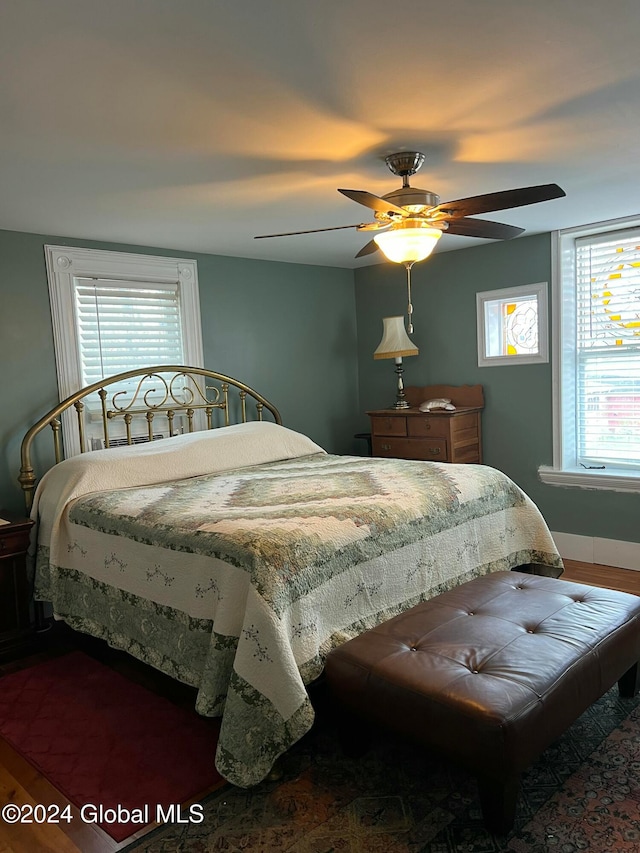 bedroom with multiple windows, ceiling fan, and dark wood-type flooring