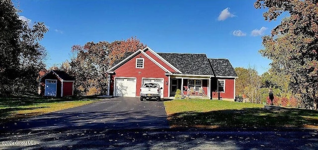 view of front of property featuring a front yard, a storage shed, and covered porch