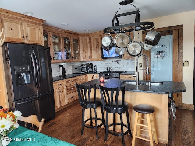 kitchen featuring sink, dark hardwood / wood-style floors, a kitchen island with sink, and black appliances