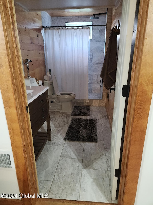 bathroom with wood walls, vanity, a shower with shower curtain, and toilet