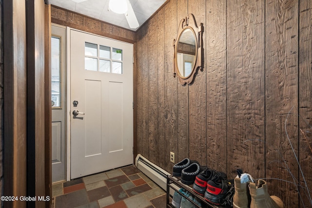 entryway featuring baseboard heating, wood walls, and ceiling fan