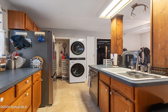 kitchen featuring appliances with stainless steel finishes, a center island, stacked washing maching and dryer, and sink