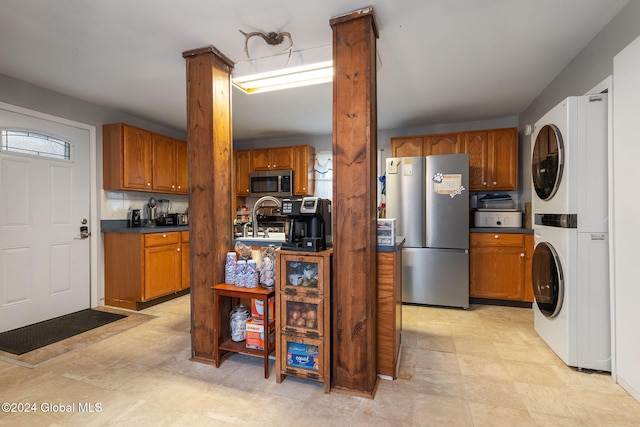 kitchen featuring stacked washing maching and dryer, stainless steel appliances, and sink