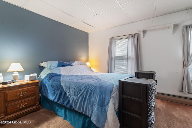 bedroom with a paneled ceiling, carpet floors, and a baseboard heating unit