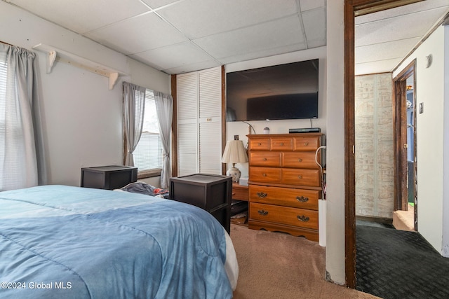 carpeted bedroom featuring a drop ceiling