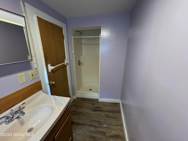 bathroom featuring hardwood / wood-style flooring, vanity, and a shower