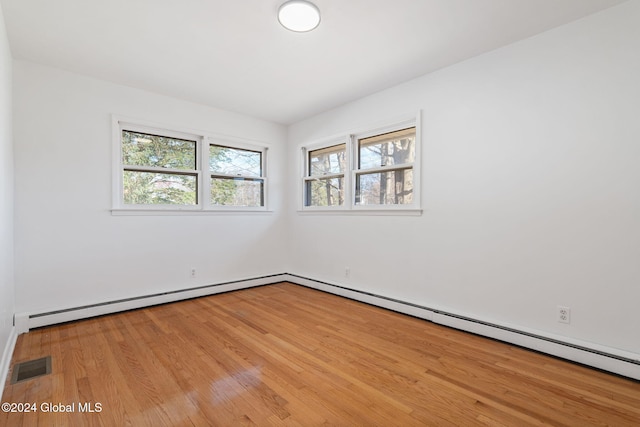 spare room with baseboard heating and light wood-type flooring