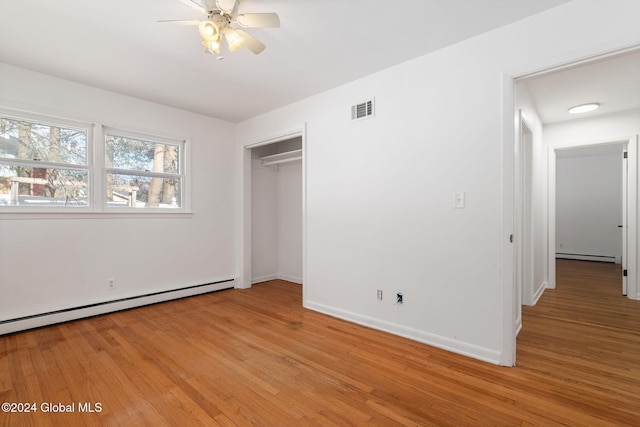 unfurnished bedroom featuring a closet, light hardwood / wood-style floors, baseboard heating, and ceiling fan