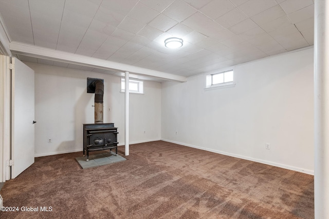 basement featuring carpet, a wood stove, and a wealth of natural light