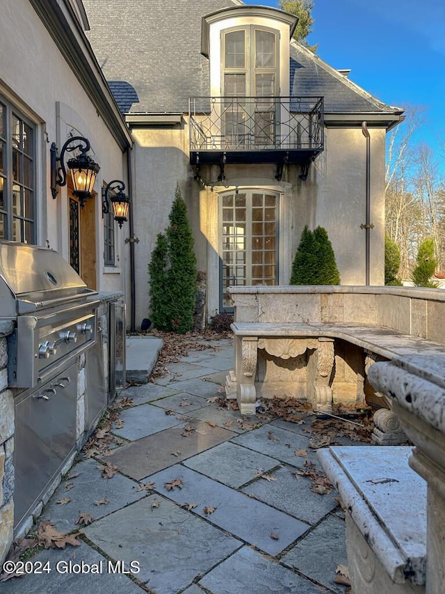 view of patio featuring a balcony, area for grilling, and exterior kitchen