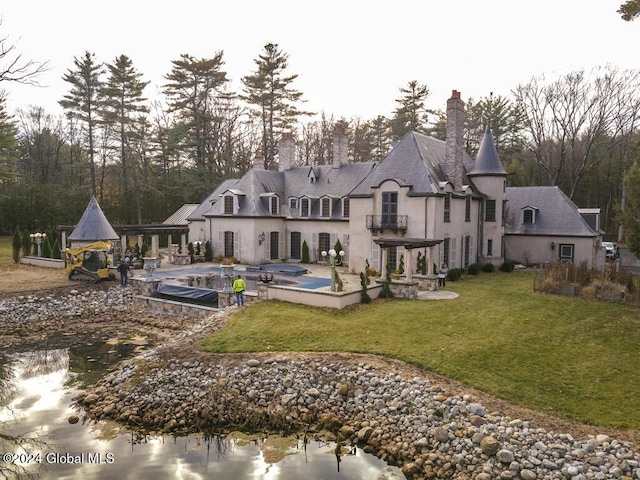 rear view of house featuring a lawn, a balcony, a patio, and a pool with hot tub