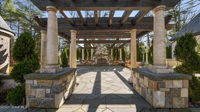 view of patio with an outdoor stone fireplace and a pergola