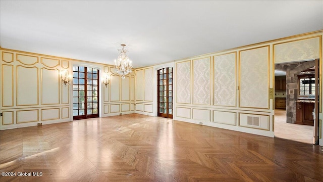 spare room with a chandelier and parquet flooring