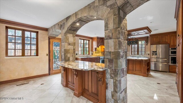 kitchen with appliances with stainless steel finishes, a wealth of natural light, and ornamental molding