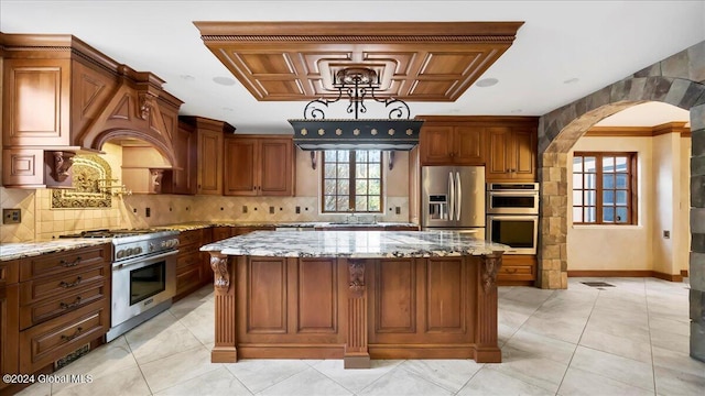 kitchen with light stone countertops, decorative backsplash, stainless steel appliances, and a kitchen island