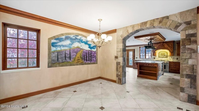 interior space with an inviting chandelier, a healthy amount of sunlight, and ornamental molding