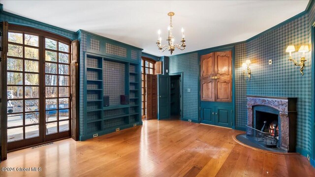 interior space with hardwood / wood-style flooring, ornamental molding, and an inviting chandelier