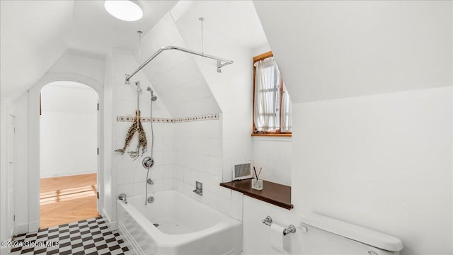 bathroom with toilet and tiled shower / bath