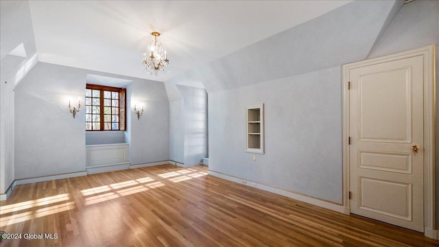 spare room featuring a chandelier, hardwood / wood-style floors, and vaulted ceiling