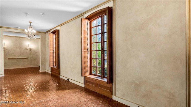 hallway with a notable chandelier and crown molding