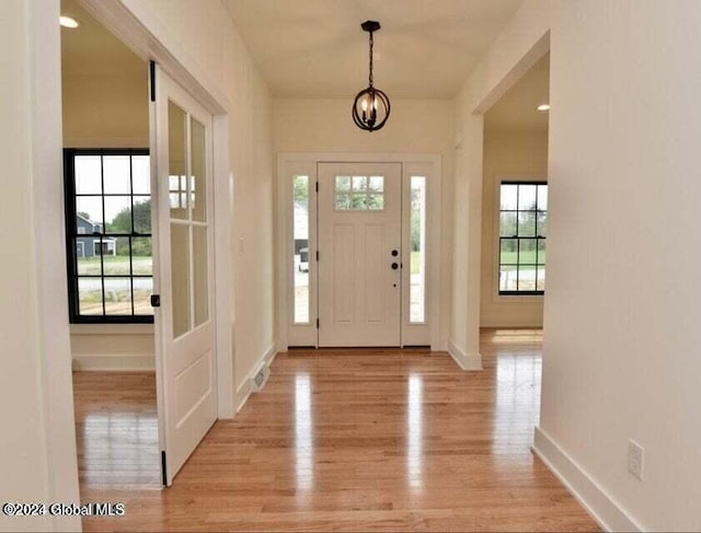 foyer entrance featuring light wood-type flooring and a notable chandelier