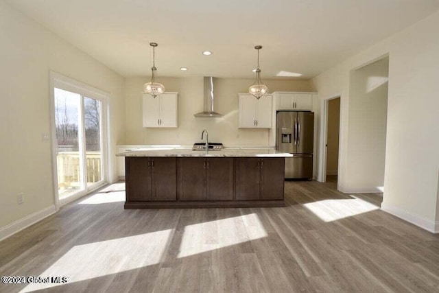 kitchen with white cabinets, stainless steel fridge with ice dispenser, light hardwood / wood-style floors, and wall chimney exhaust hood