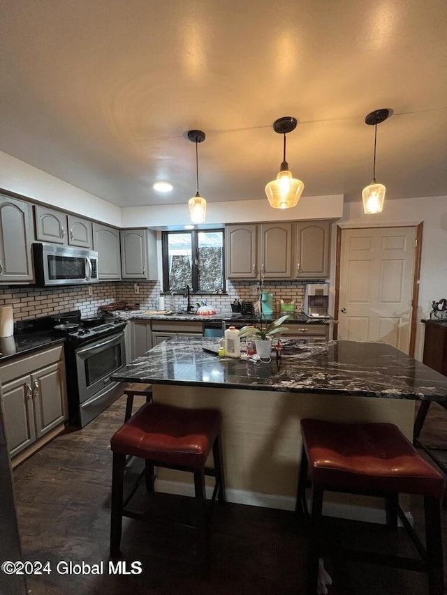 kitchen with a center island, tasteful backsplash, decorative light fixtures, a kitchen bar, and stainless steel appliances