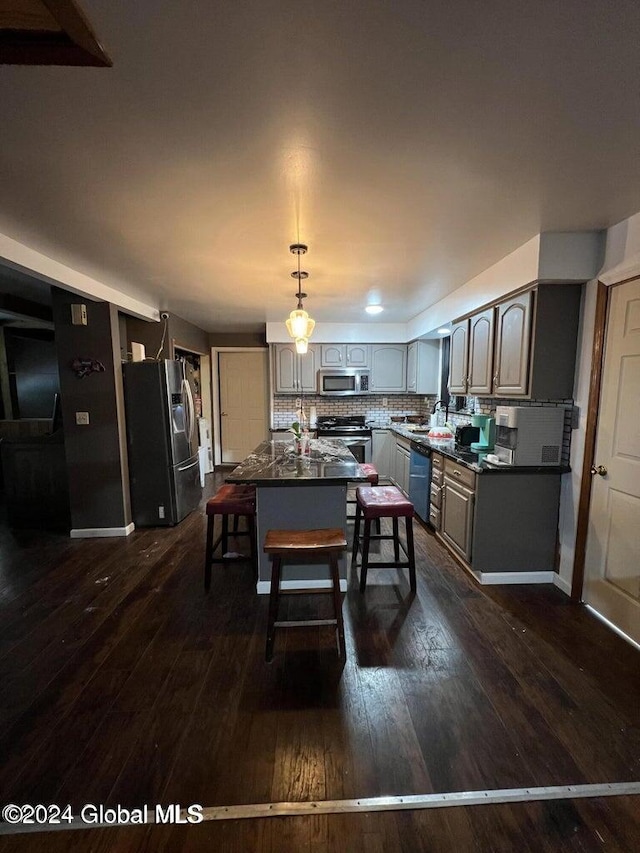 kitchen featuring appliances with stainless steel finishes, backsplash, dark wood-type flooring, pendant lighting, and gray cabinets