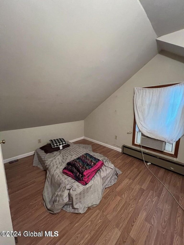 bedroom with hardwood / wood-style floors, a baseboard radiator, and lofted ceiling