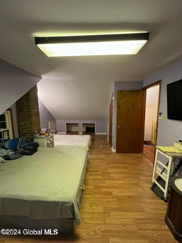 bedroom with light hardwood / wood-style floors and lofted ceiling